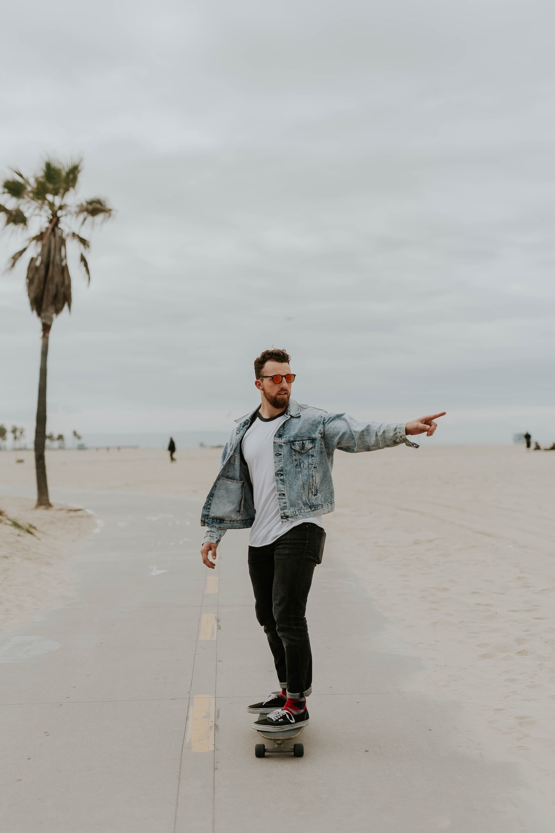 Un homme pointant au loin faisant une promenade près de la plage, sous un ciel nuageux.